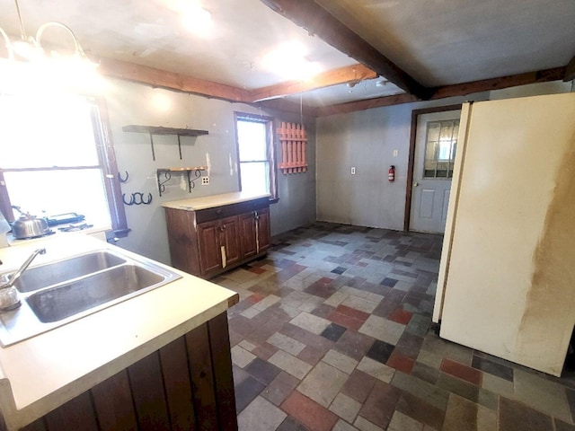 kitchen with decorative light fixtures, white refrigerator, beam ceiling, dark brown cabinetry, and sink