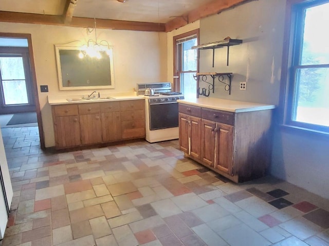 kitchen featuring decorative light fixtures, a notable chandelier, beam ceiling, sink, and white gas stove