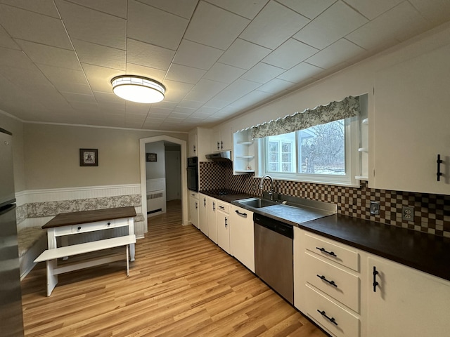 kitchen with white cabinetry, sink, radiator heating unit, stainless steel dishwasher, and black oven