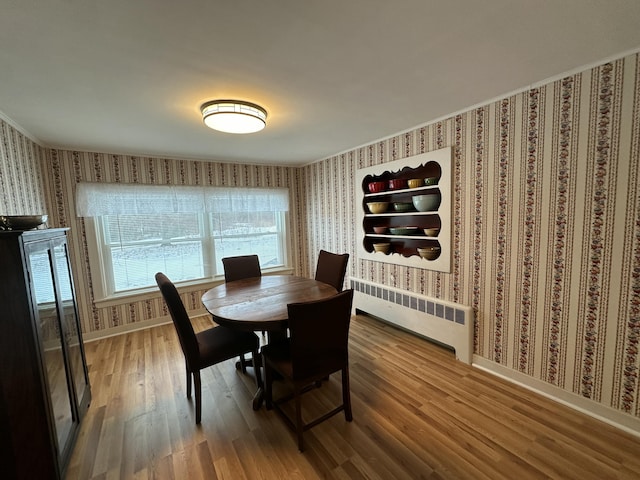 dining area with hardwood / wood-style flooring and radiator