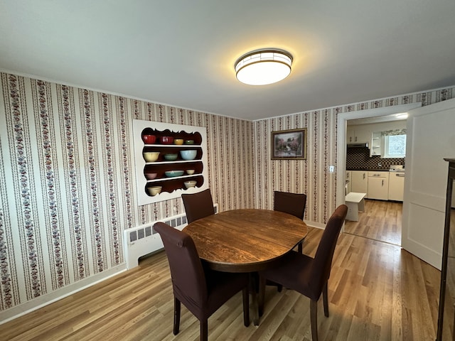 dining space with radiator heating unit and light hardwood / wood-style floors