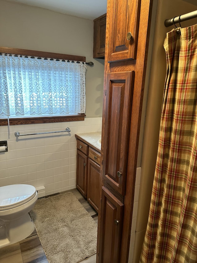 bathroom featuring vanity, toilet, and tile walls