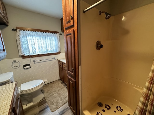 bathroom featuring vanity, tile patterned floors, toilet, tile walls, and walk in shower