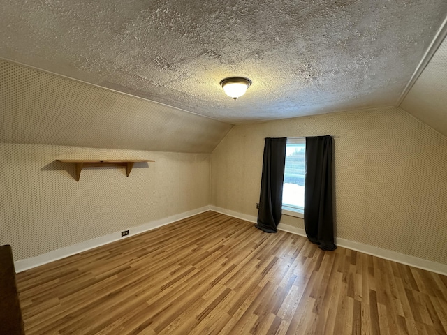 bonus room featuring wood-type flooring, a textured ceiling, and vaulted ceiling