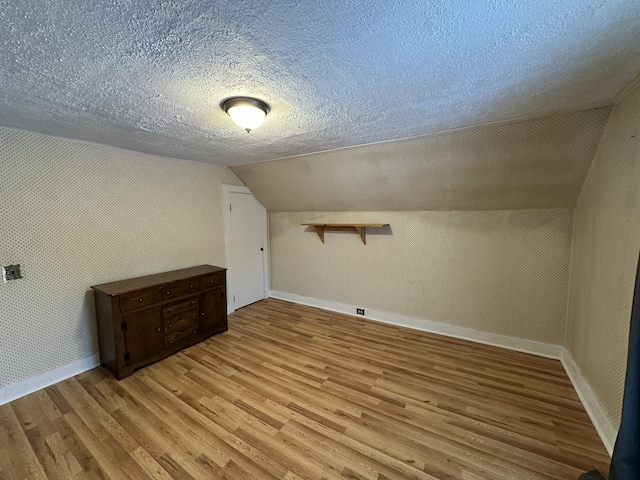 bonus room featuring a textured ceiling, light hardwood / wood-style floors, and lofted ceiling