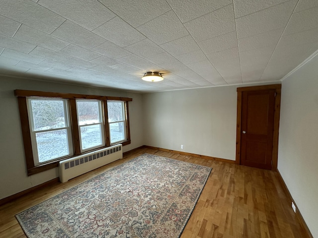 spare room with radiator heating unit and light hardwood / wood-style floors