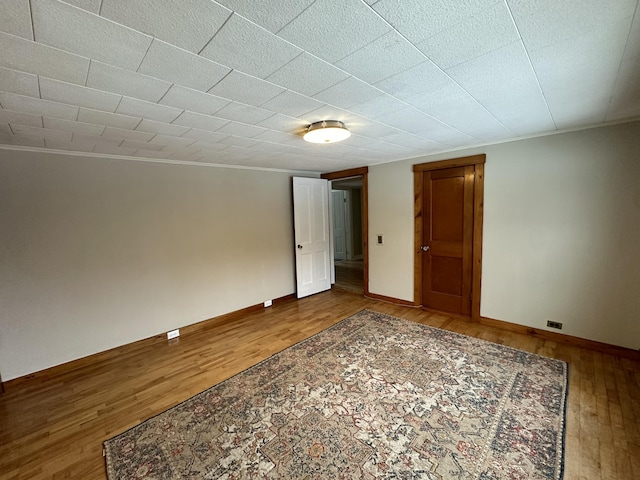 spare room featuring hardwood / wood-style flooring and ornamental molding