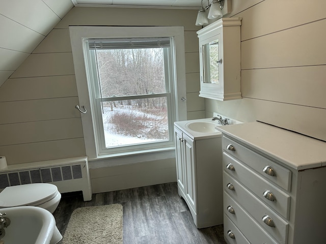 bathroom featuring radiator, hardwood / wood-style floors, vaulted ceiling, toilet, and vanity