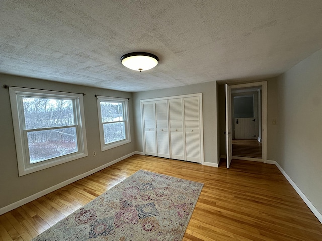 unfurnished bedroom featuring light wood-type flooring, a textured ceiling, and a closet