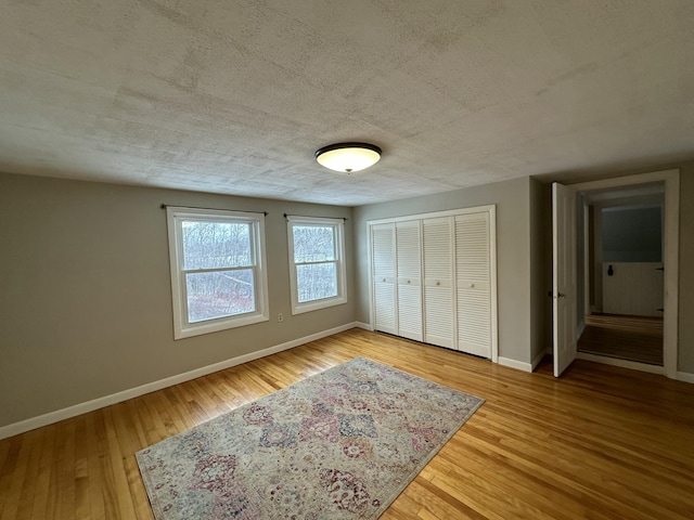 unfurnished bedroom with a closet, wood-type flooring, and a textured ceiling