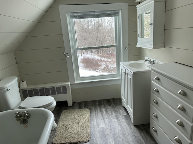 bathroom featuring hardwood / wood-style flooring, toilet, radiator, and vaulted ceiling