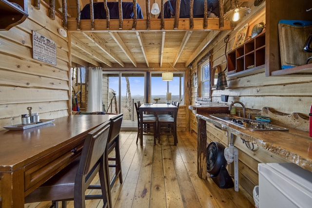 kitchen featuring sink, wooden walls, beamed ceiling, light wood-type flooring, and wood ceiling