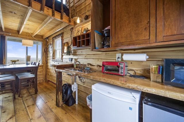 kitchen featuring wooden ceiling, wood walls, refrigerator, light stone counters, and light hardwood / wood-style flooring