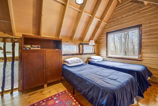 bedroom featuring light wood-type flooring, wood walls, vaulted ceiling with beams, and multiple windows