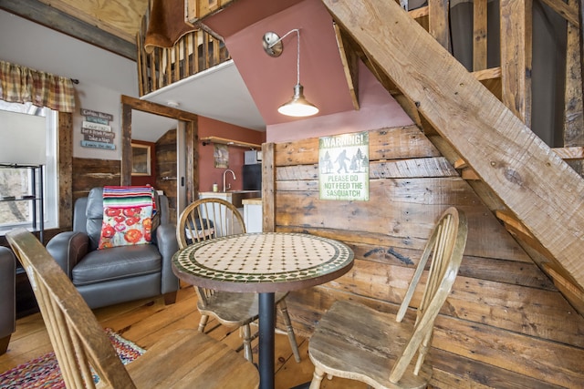 dining area with sink, wood-type flooring, and wood walls