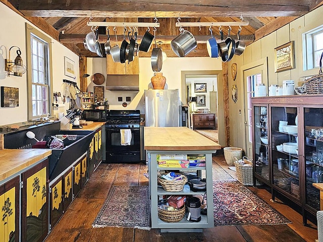 kitchen with black gas range, wood ceiling, rail lighting, stainless steel refrigerator, and beamed ceiling