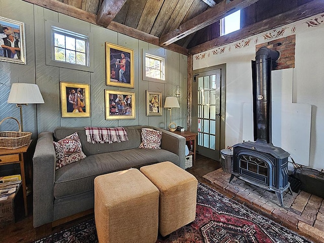 living room with a healthy amount of sunlight, wooden ceiling, a wood stove, and vaulted ceiling with beams