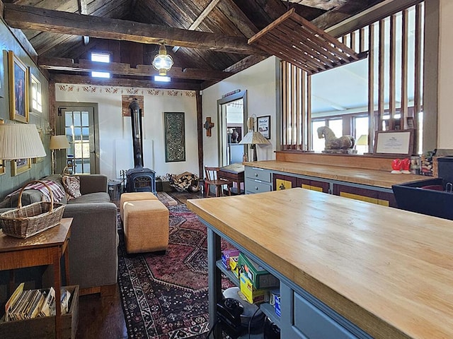 interior space with a wood stove, wood ceiling, and vaulted ceiling with beams