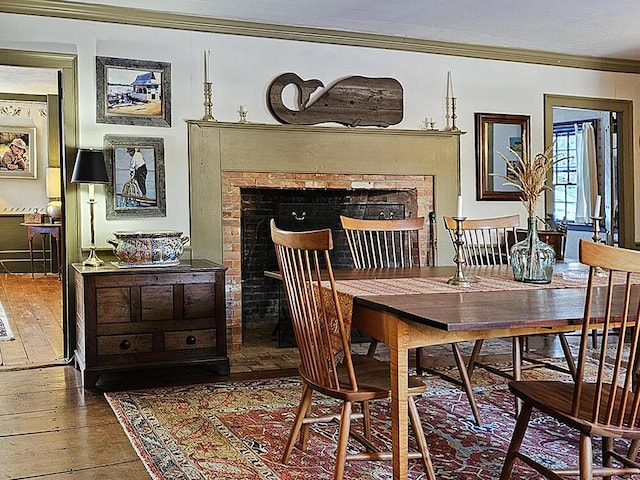 dining space with a fireplace, ornamental molding, and hardwood / wood-style flooring