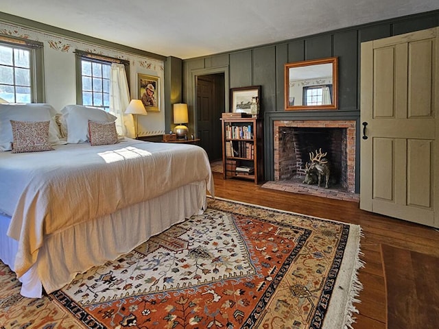 bedroom featuring a brick fireplace and dark hardwood / wood-style flooring