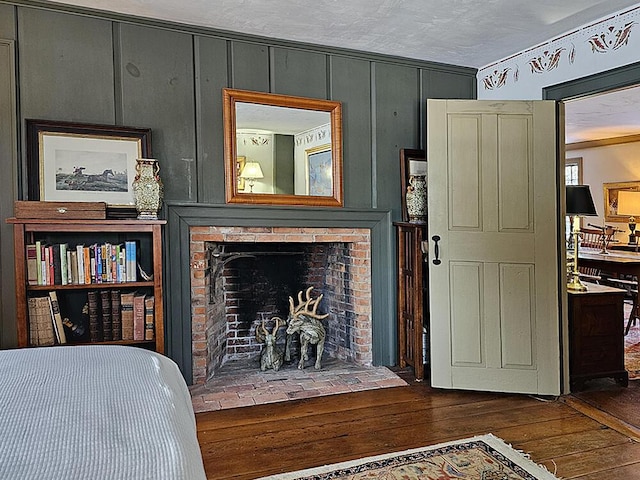 bedroom featuring a textured ceiling, ornamental molding, a fireplace, and dark hardwood / wood-style floors