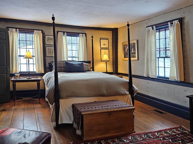 bedroom with dark hardwood / wood-style flooring and multiple windows