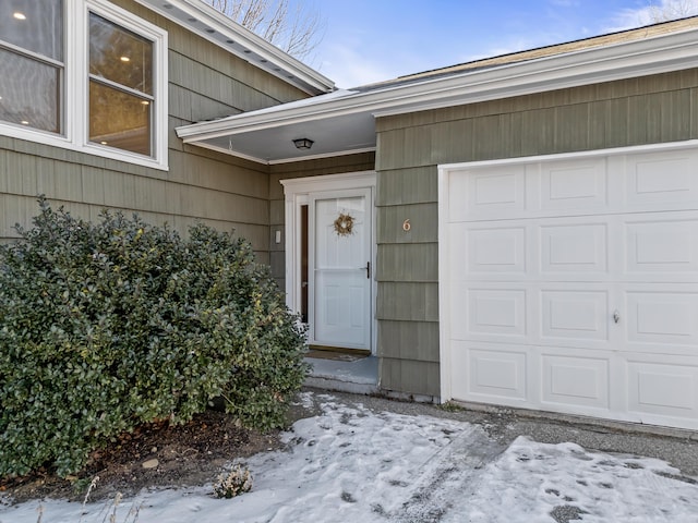 snow covered property entrance with a garage