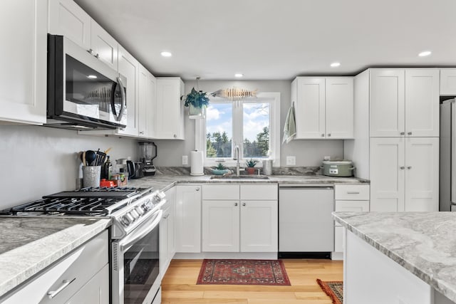 kitchen with stainless steel appliances, light hardwood / wood-style floors, white cabinetry, and sink