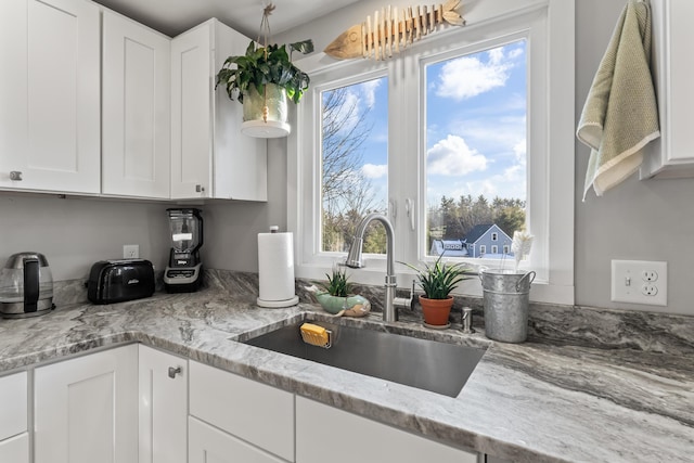 kitchen featuring a wealth of natural light, white cabinetry, and sink