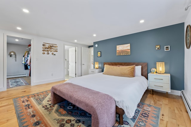 bedroom with ensuite bathroom, baseboard heating, a spacious closet, and a closet