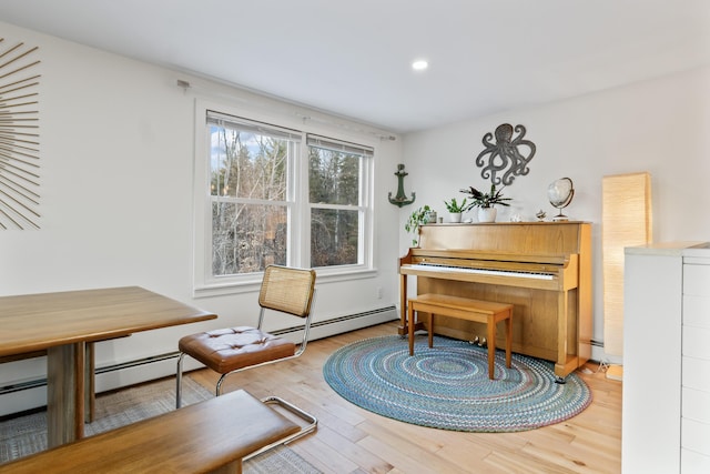 living area with a baseboard heating unit and light hardwood / wood-style flooring