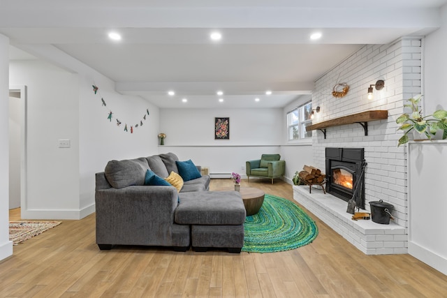 living room featuring a baseboard radiator, light hardwood / wood-style flooring, beam ceiling, and a fireplace