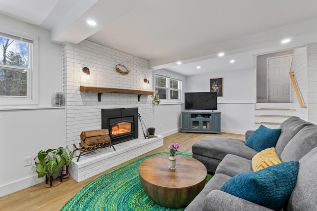 living room with beam ceiling, a fireplace, and light hardwood / wood-style floors