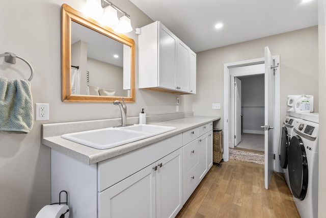 laundry room featuring washer and clothes dryer, light wood-type flooring, and sink