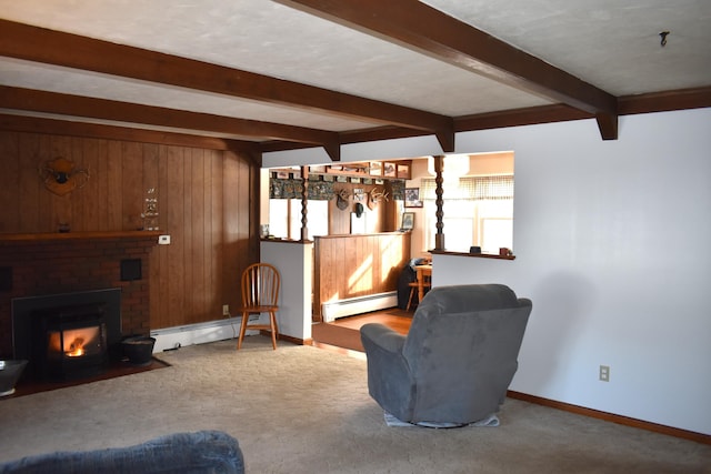 carpeted living room with beamed ceiling, a brick fireplace, a baseboard heating unit, and wood walls