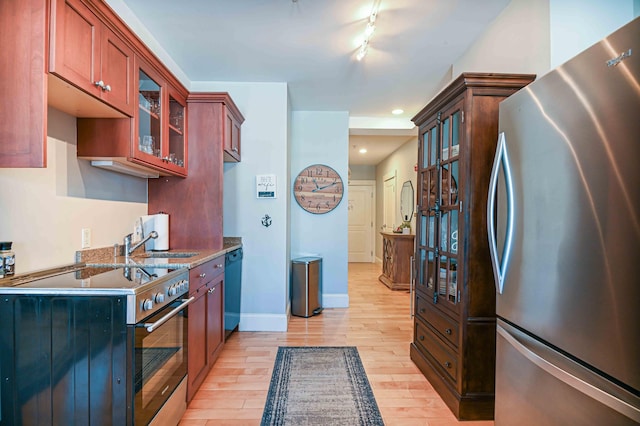 kitchen with appliances with stainless steel finishes, rail lighting, light hardwood / wood-style flooring, and sink