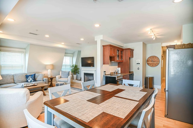 dining space with rail lighting and light hardwood / wood-style flooring