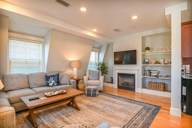 living room with built in features and light hardwood / wood-style floors