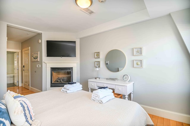 bedroom with connected bathroom and light hardwood / wood-style floors