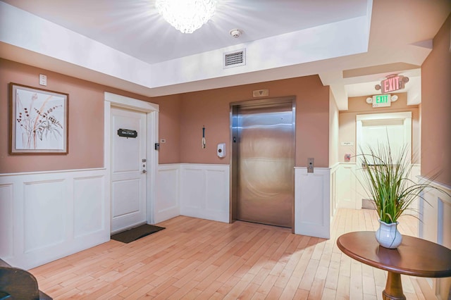 foyer with elevator, a chandelier, and light hardwood / wood-style floors