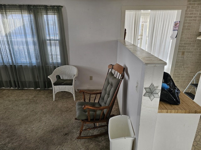 sitting room featuring brick wall and carpet flooring