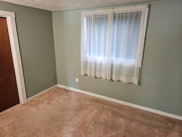 carpeted empty room with a textured ceiling