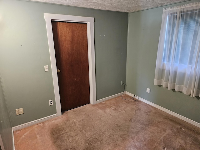 unfurnished room featuring a textured ceiling and carpet