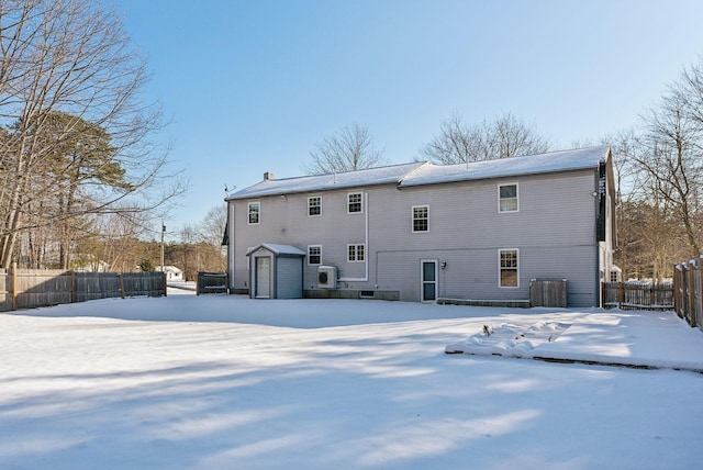 snow covered back of property featuring a storage shed and ac unit