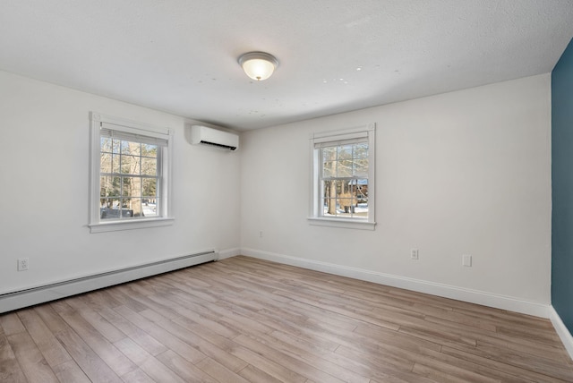 empty room with a baseboard radiator, an AC wall unit, plenty of natural light, and light hardwood / wood-style floors