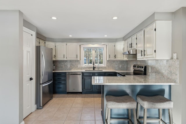 kitchen featuring sink, a breakfast bar area, light tile patterned floors, appliances with stainless steel finishes, and kitchen peninsula