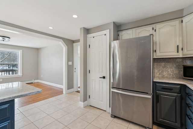 kitchen with backsplash, light tile patterned flooring, white cabinets, and appliances with stainless steel finishes