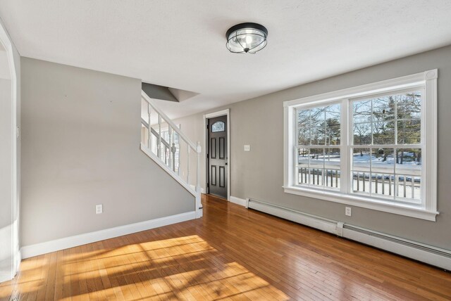 foyer entrance with wood-type flooring, a healthy amount of sunlight, and baseboard heating