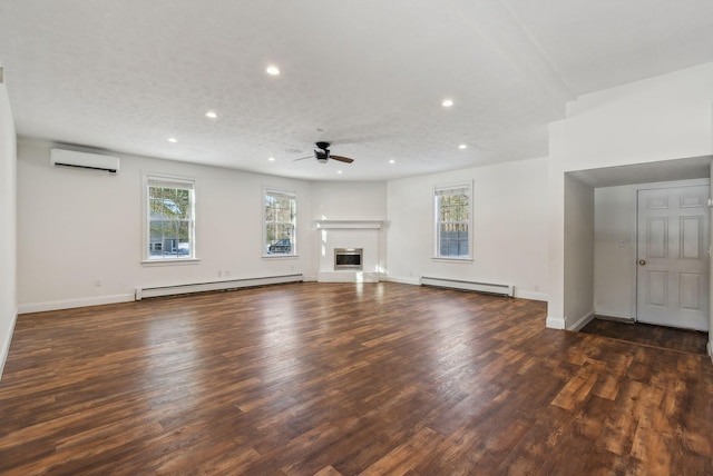 unfurnished living room featuring an AC wall unit, a healthy amount of sunlight, and baseboard heating