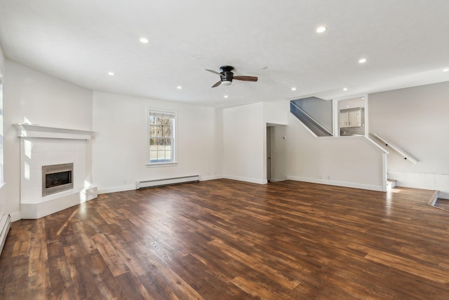 unfurnished living room featuring baseboard heating, a fireplace, dark hardwood / wood-style floors, and ceiling fan